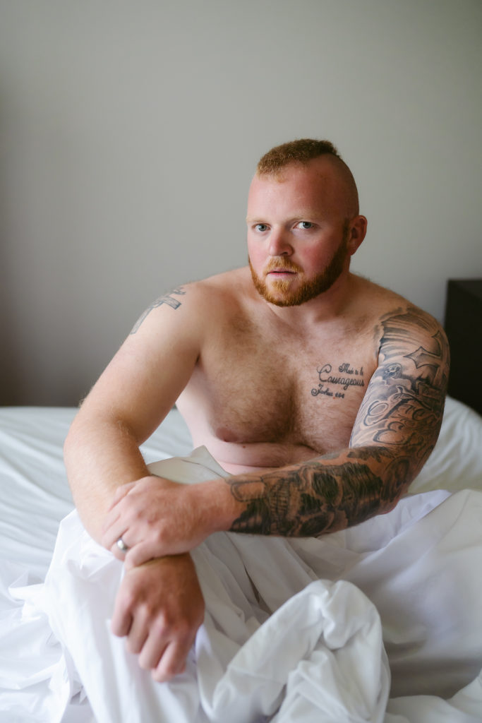 Male boudoir with white sheets and tattoos and beard